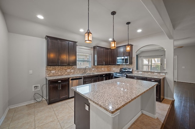 kitchen with light tile patterned floors, appliances with stainless steel finishes, light stone counters, and backsplash