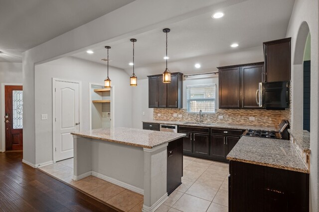 kitchen with light tile patterned flooring, a center island, appliances with stainless steel finishes, light stone counters, and tasteful backsplash