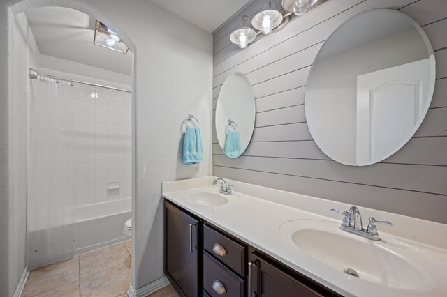 full bathroom with toilet, wooden walls, shower / bath combo with shower curtain, vanity, and tile patterned floors