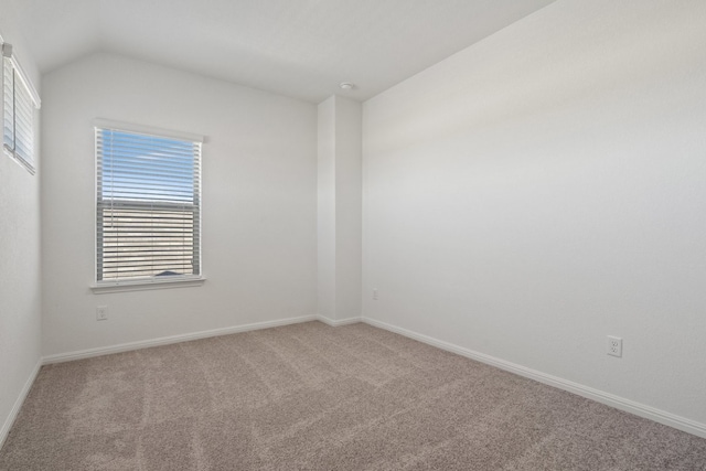 carpeted empty room featuring lofted ceiling