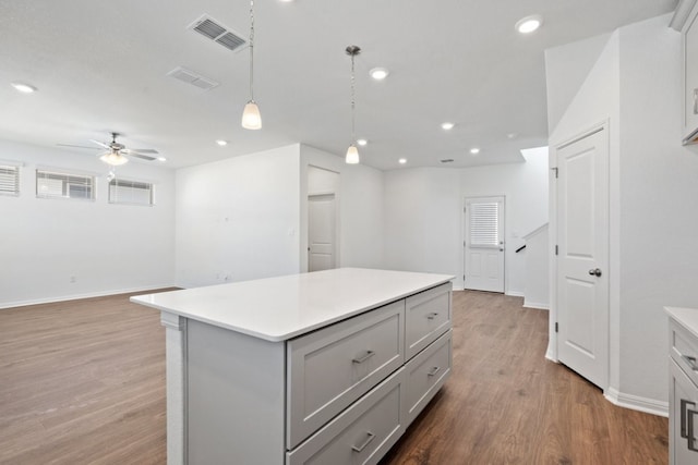 kitchen featuring hardwood / wood-style flooring, hanging light fixtures, a center island, gray cabinets, and ceiling fan