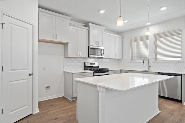 kitchen featuring a center island, white cabinetry, stainless steel appliances, and decorative light fixtures