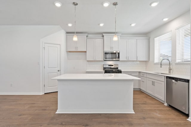 kitchen featuring hanging light fixtures, stainless steel appliances, sink, a center island, and white cabinetry