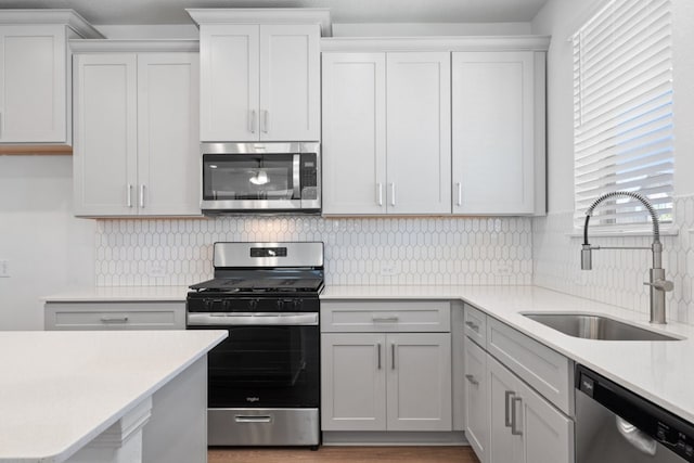 kitchen with sink, appliances with stainless steel finishes, white cabinetry, and tasteful backsplash