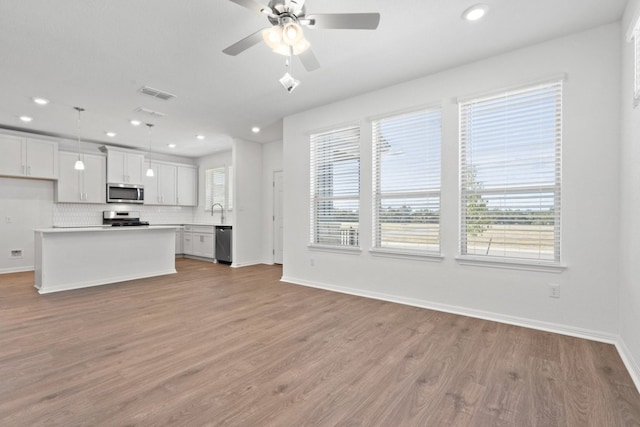 unfurnished living room with sink, light wood-type flooring, and ceiling fan