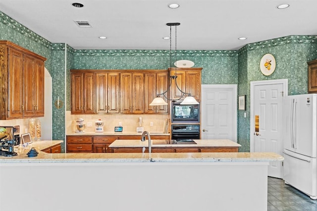 kitchen featuring pendant lighting, black appliances, brown cabinets, and wallpapered walls