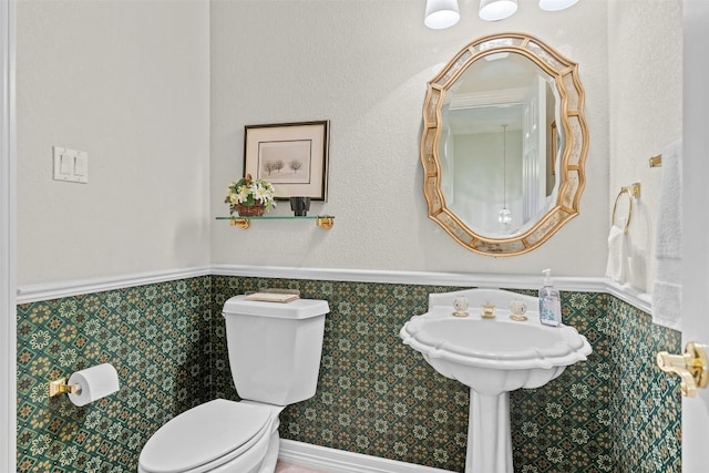 half bath featuring toilet and a wainscoted wall