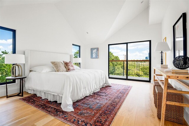 bedroom featuring light hardwood / wood-style flooring, access to exterior, and high vaulted ceiling