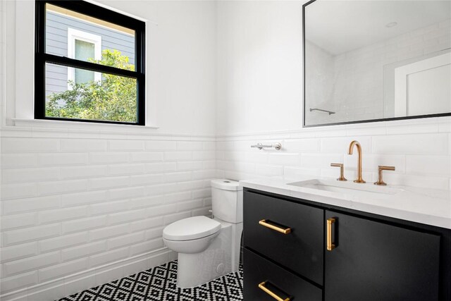 bathroom with vanity, toilet, and tile walls