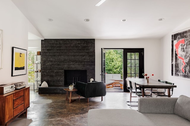 living room featuring a large fireplace, concrete flooring, and french doors