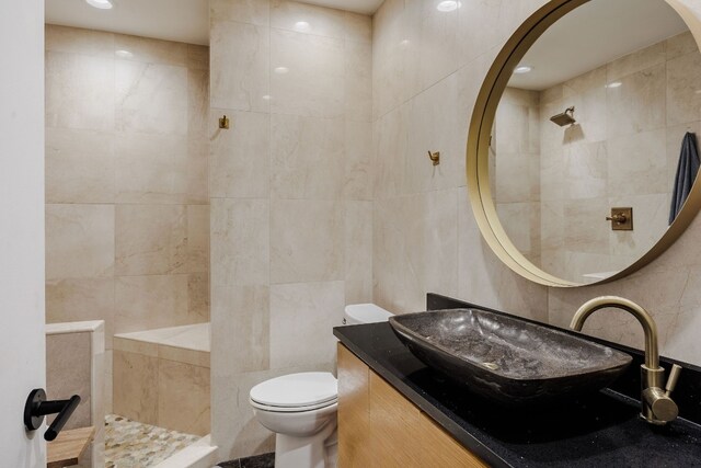 bathroom with tile walls, vanity, and toilet