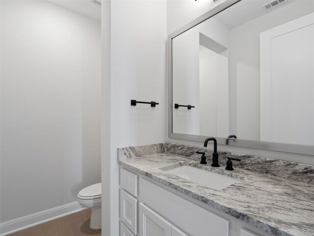 bathroom with toilet, vanity, and hardwood / wood-style flooring