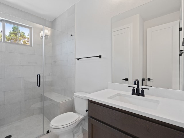 bathroom featuring a shower with door, vanity, and toilet