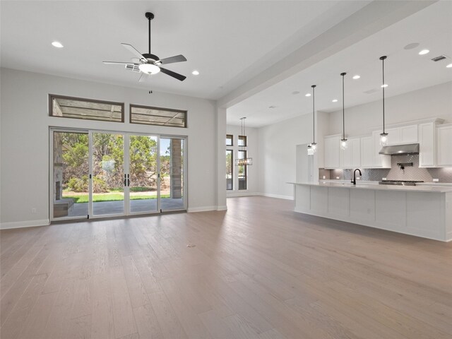 unfurnished living room featuring light hardwood / wood-style floors, ceiling fan, and a healthy amount of sunlight