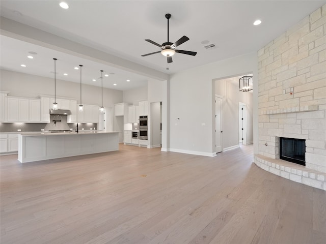 unfurnished living room featuring a fireplace, ceiling fan, and light wood-type flooring