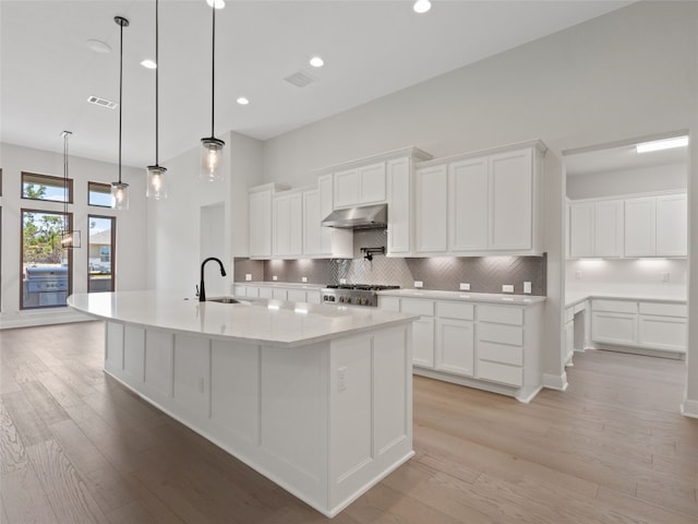 kitchen with backsplash, light hardwood / wood-style flooring, and white cabinets