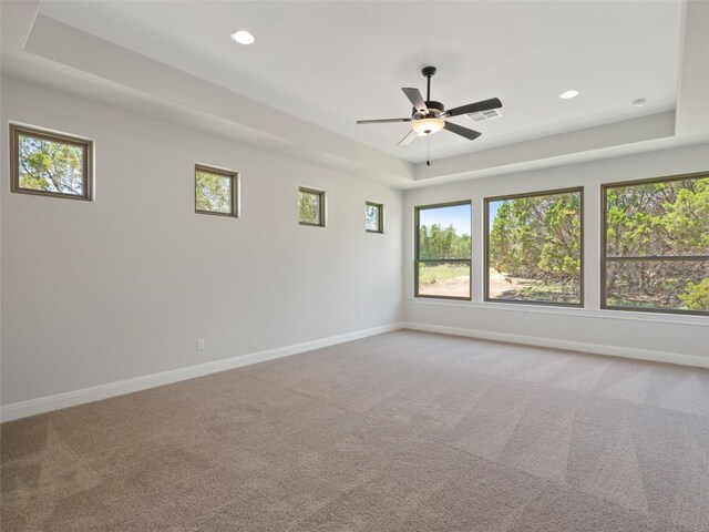 empty room featuring ceiling fan, a tray ceiling, and carpet flooring