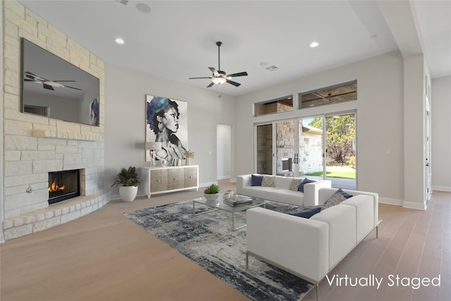 living room featuring light hardwood / wood-style floors, ceiling fan, and a fireplace