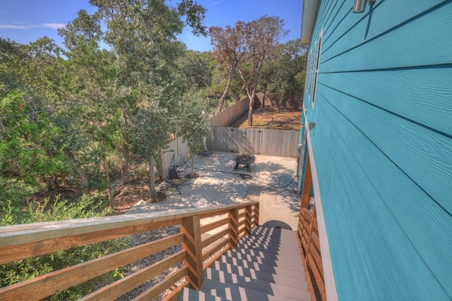 wooden terrace with a patio area, a fire pit, and a fenced backyard