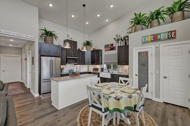 kitchen featuring dark wood-style flooring, a center island, appliances with stainless steel finishes, high vaulted ceiling, and a sink