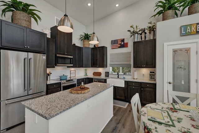 kitchen with a sink, stainless steel appliances, dark wood-type flooring, decorative backsplash, and a kitchen island
