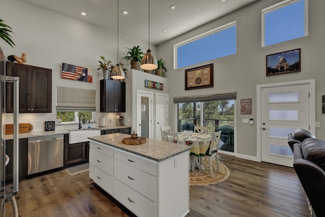 kitchen with pendant lighting, dishwasher, dark wood-type flooring, a high ceiling, and sink