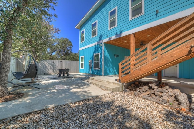 view of side of property featuring a patio area, board and batten siding, fence, and a ceiling fan