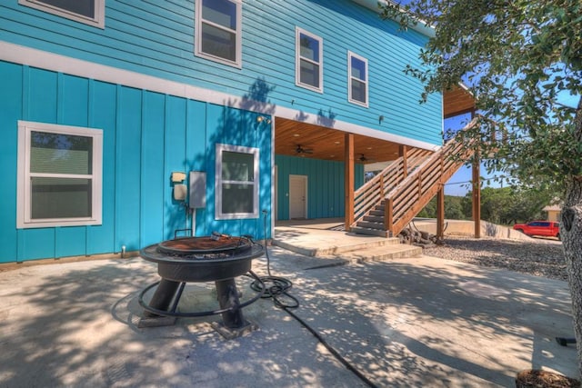 rear view of house featuring stairway, board and batten siding, a patio area, an outdoor fire pit, and ceiling fan