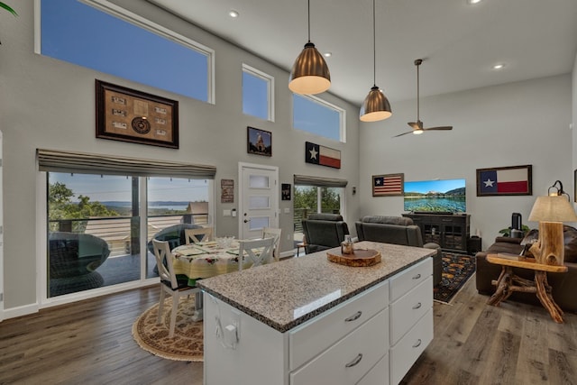 kitchen featuring a towering ceiling, a kitchen island, ceiling fan, dark hardwood / wood-style floors, and white cabinetry