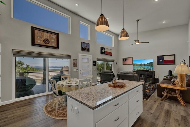kitchen with hanging light fixtures, white cabinets, a center island, a ceiling fan, and dark wood-style floors