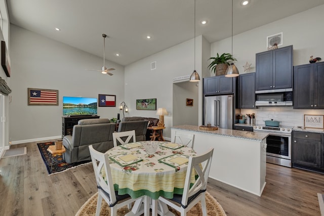 dining area with ceiling fan, light wood-type flooring, and high vaulted ceiling