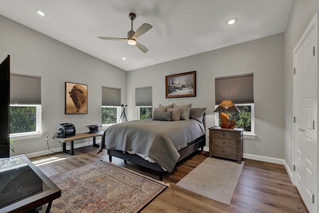 bedroom featuring hardwood / wood-style floors, multiple windows, lofted ceiling, and ceiling fan