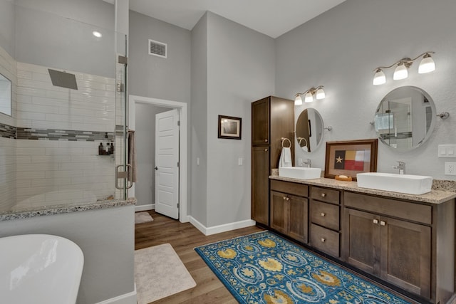 bathroom with plus walk in shower, hardwood / wood-style floors, and vanity