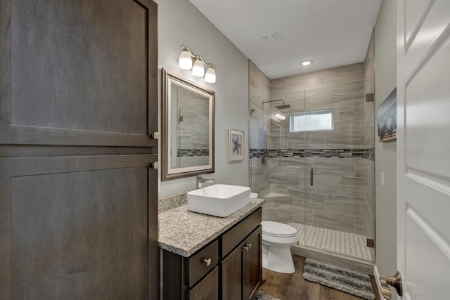 bathroom with toilet, a shower stall, vanity, and wood finished floors