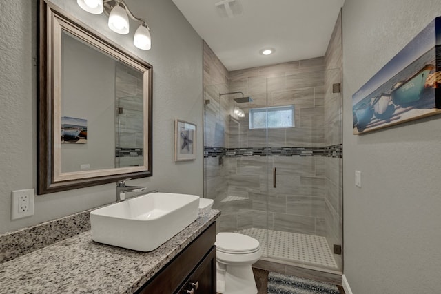 bathroom featuring vanity, toilet, and a shower with shower door