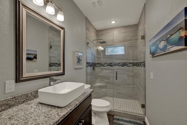 full bath with vanity, visible vents, a stall shower, and toilet