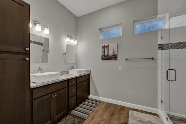 bathroom featuring a shower stall, baseboards, a sink, and wood finished floors