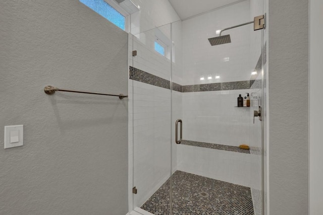 bathroom with a textured wall and a stall shower