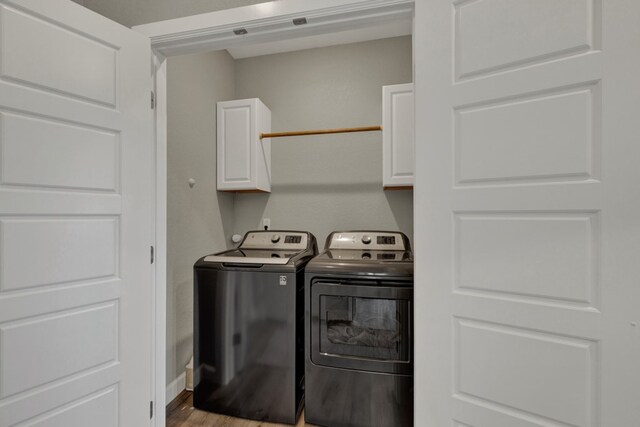 laundry room with cabinets, washing machine and dryer, and hardwood / wood-style flooring