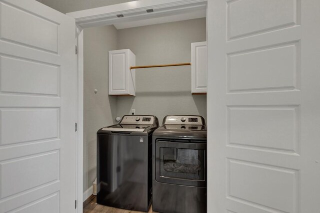 washroom with baseboards, washer and clothes dryer, wood finished floors, and cabinet space