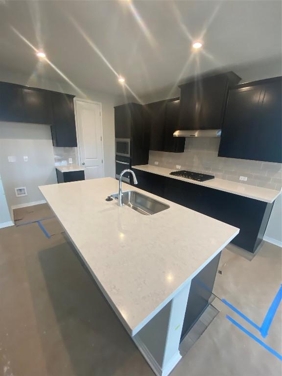 kitchen featuring a kitchen island with sink, sink, decorative backsplash, and black appliances