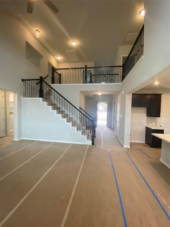 stairs featuring ceiling fan and a towering ceiling