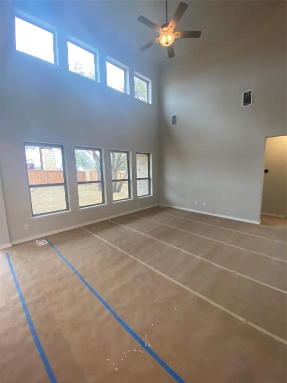 interior space featuring plenty of natural light, a towering ceiling, and ceiling fan