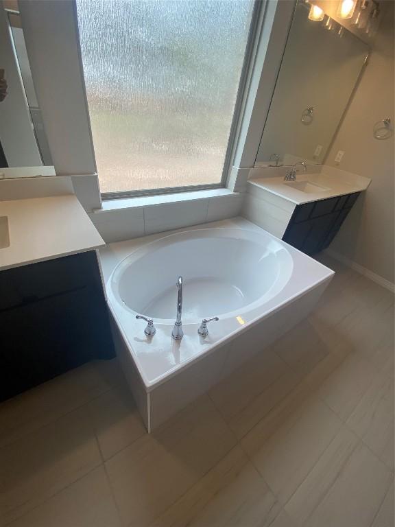 bathroom with tile patterned floors, vanity, and a tub