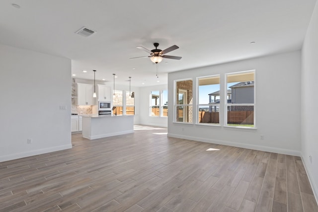 unfurnished living room featuring light hardwood / wood-style floors, a wealth of natural light, and ceiling fan