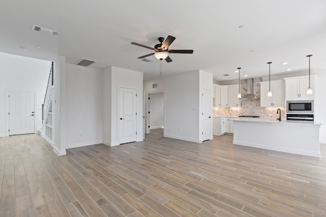 unfurnished living room featuring light hardwood / wood-style flooring, ceiling fan, and sink