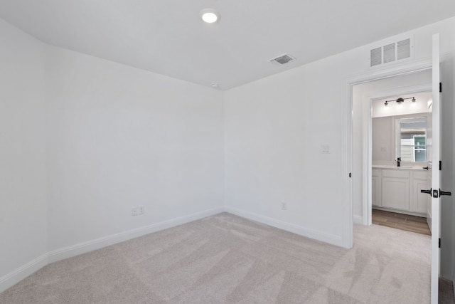 spare room featuring light carpet and sink