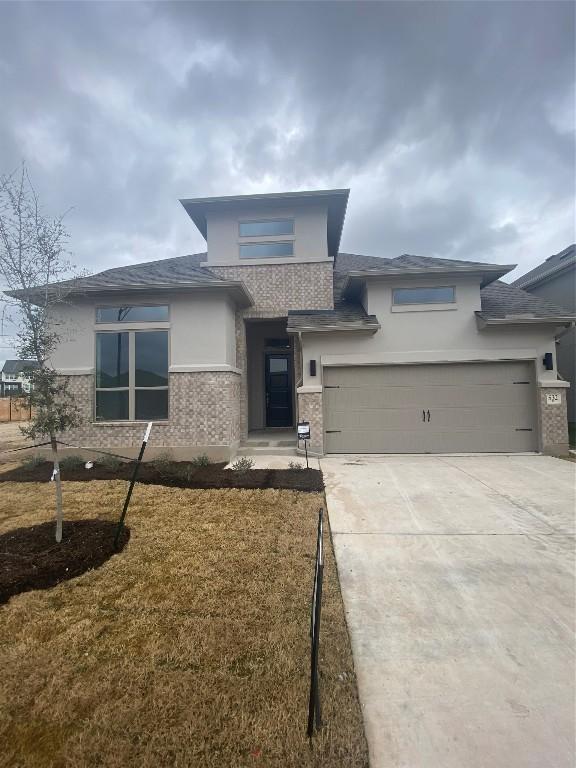 prairie-style home with a garage and a front lawn