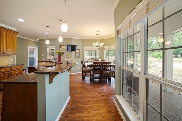 kitchen with a breakfast bar, backsplash, ornamental molding, a chandelier, and dark hardwood / wood-style floors