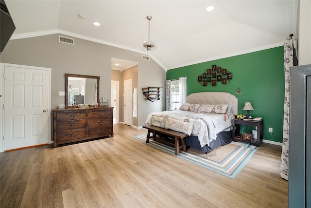 bedroom featuring light wood-type flooring, vaulted ceiling, ornamental molding, and ceiling fan